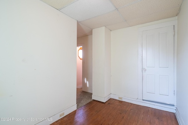 spare room with a drop ceiling and dark hardwood / wood-style floors