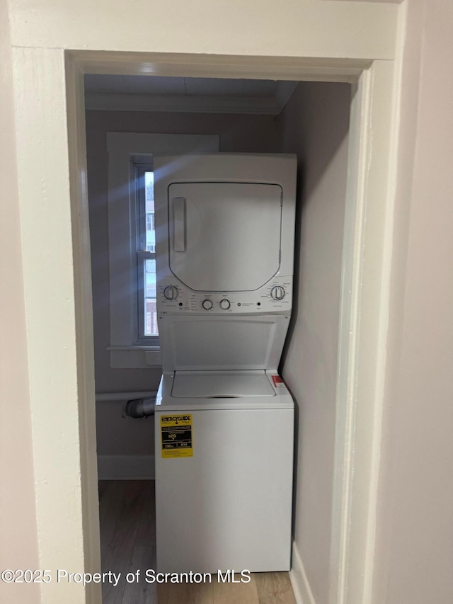 clothes washing area featuring hardwood / wood-style flooring and stacked washer and clothes dryer