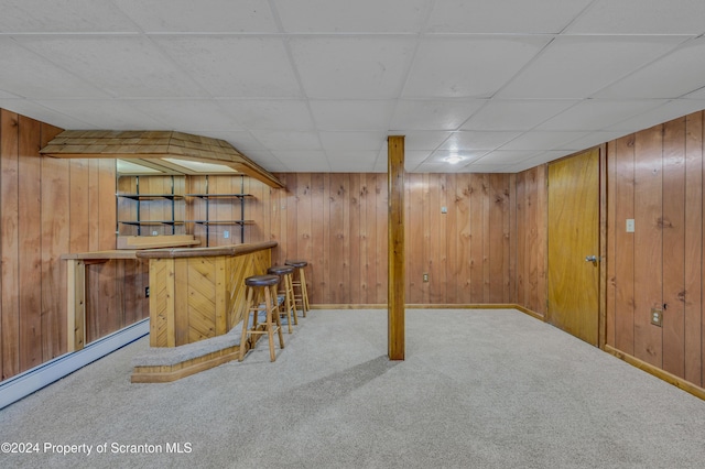 bar featuring carpet flooring, a paneled ceiling, baseboard heating, and wooden walls