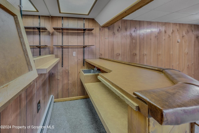 bar with a paneled ceiling, wooden walls, light colored carpet, and a baseboard radiator