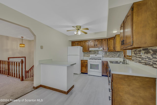 kitchen with white appliances, backsplash, hanging light fixtures, and sink