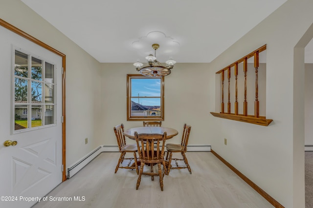 dining room featuring an inviting chandelier, light hardwood / wood-style flooring, and a baseboard heating unit