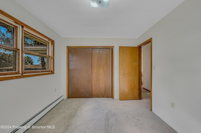 unfurnished bedroom with light carpet, a closet, and a baseboard radiator