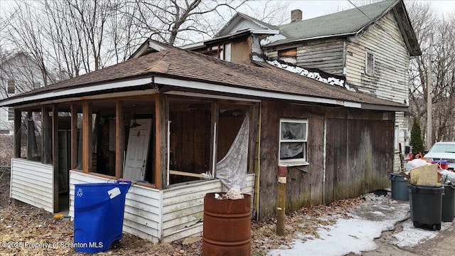 view of property exterior with a shingled roof and a sunroom