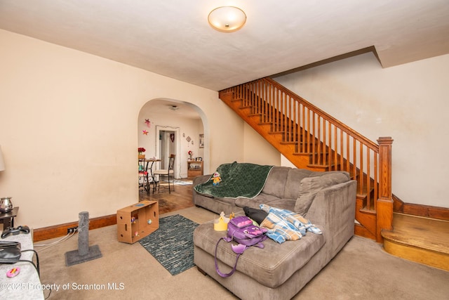 living room with arched walkways, stairway, carpet flooring, and baseboards