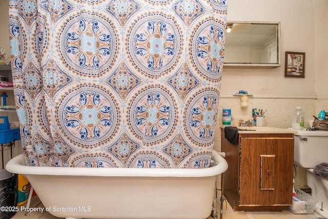 full bathroom featuring tile walls, a freestanding tub, and toilet