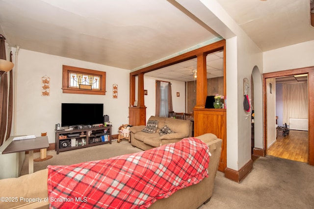 carpeted living area featuring baseboards and arched walkways