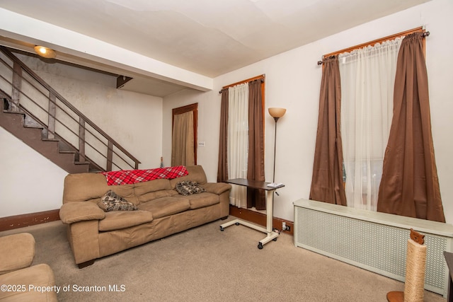 carpeted living area featuring stairway, radiator, and baseboards