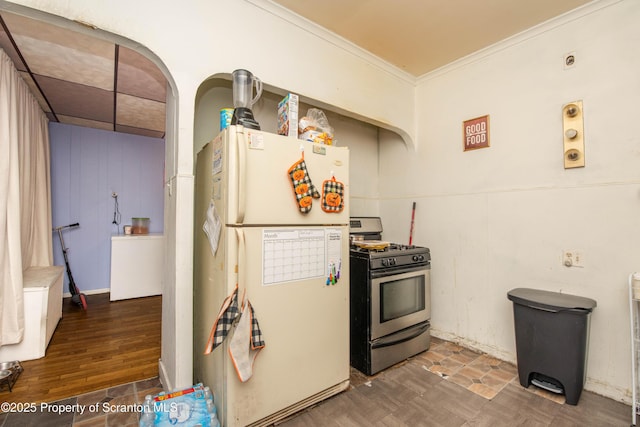 kitchen with gas stove, wood finished floors, ornamental molding, and freestanding refrigerator