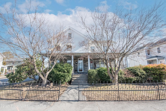 view of front of home with a fenced front yard, stone siding, and a porch