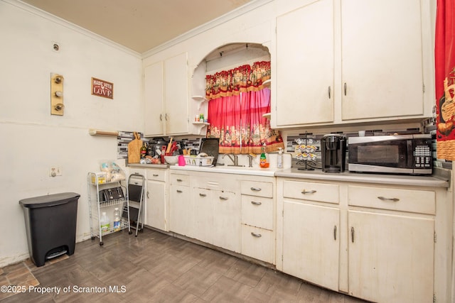 kitchen with stainless steel microwave, light countertops, and ornamental molding