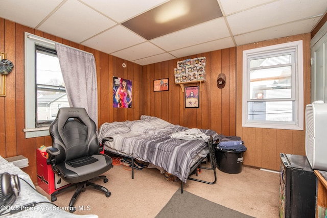 bedroom with carpet flooring, multiple windows, and wood walls