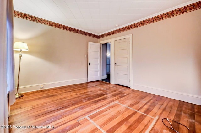 empty room with ornamental molding and hardwood / wood-style floors