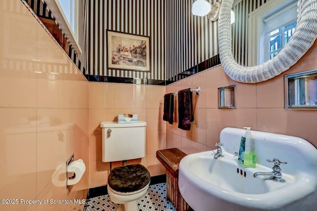 bathroom featuring toilet, sink, and tile walls