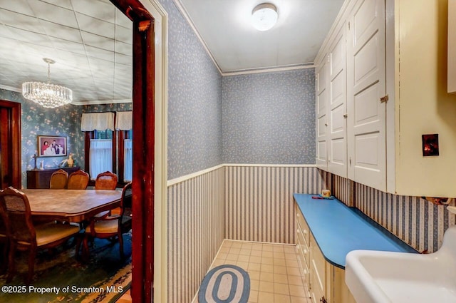 bathroom with an inviting chandelier, tile patterned floors, and ornamental molding