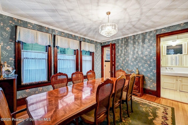 dining area featuring crown molding, sink, an inviting chandelier, and hardwood / wood-style flooring