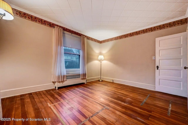 empty room featuring wood-type flooring, ornamental molding, and radiator heating unit