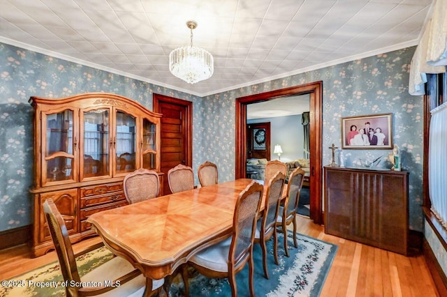 dining space featuring ornamental molding, light wood-type flooring, and a chandelier