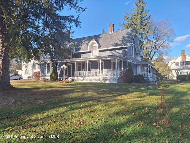 rear view of property featuring a porch and a yard