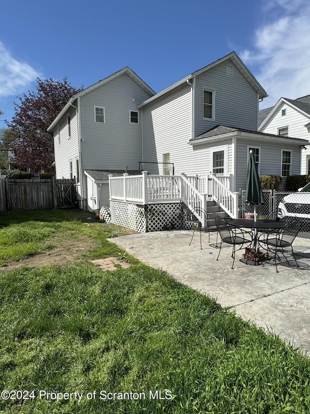 back of house featuring a wooden deck, a yard, and a patio