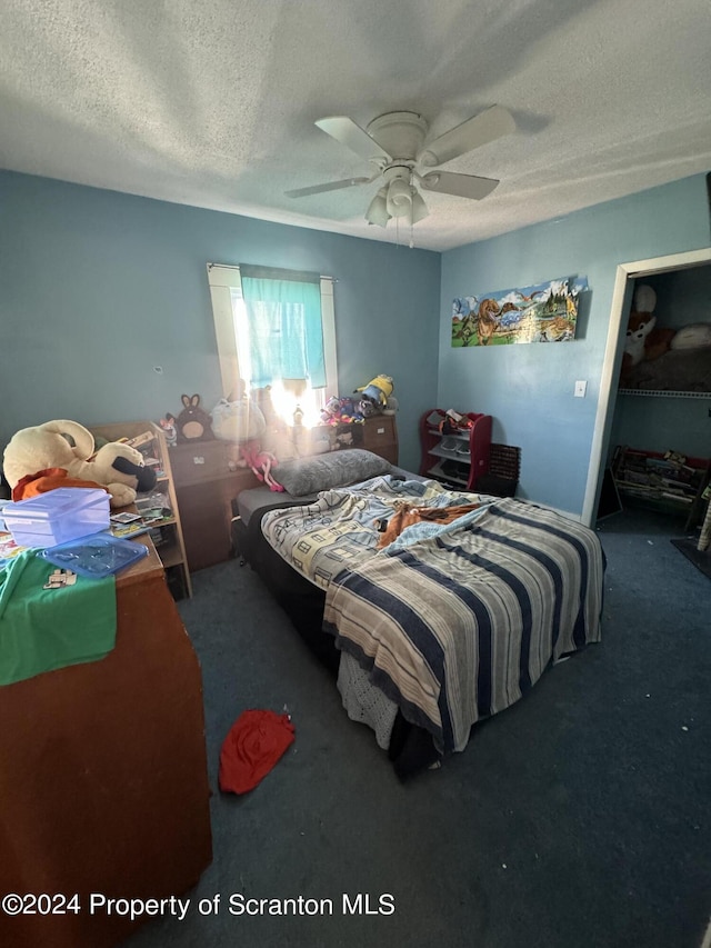 carpeted bedroom with ceiling fan and a textured ceiling