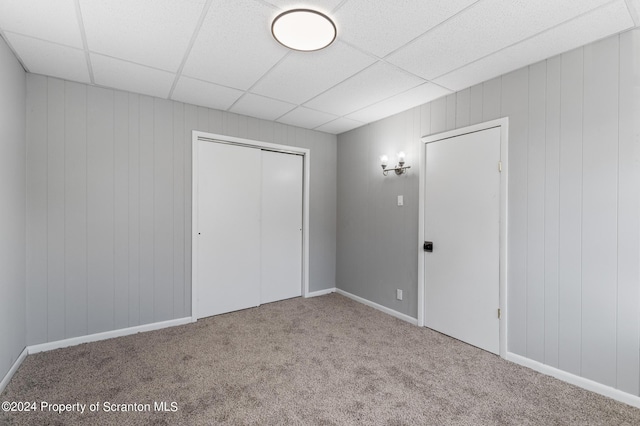 unfurnished bedroom featuring a closet, carpet floors, and a drop ceiling