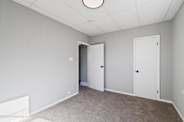 carpeted empty room featuring a drop ceiling