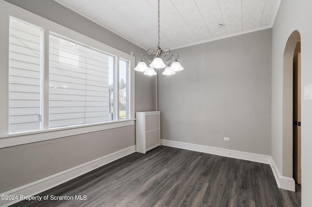 unfurnished dining area featuring crown molding, dark wood-type flooring, and a notable chandelier