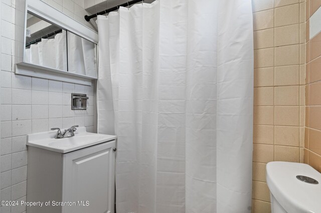 bathroom with vanity, toilet, and tile walls