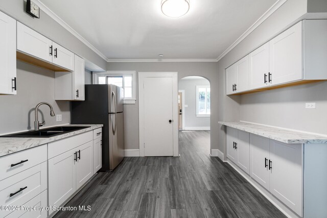 kitchen featuring light stone countertops, white cabinetry, sink, and ornamental molding