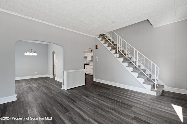 unfurnished living room with dark wood-type flooring, crown molding, and a notable chandelier