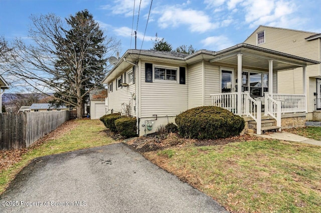 view of front of home with a front yard, an outdoor structure, and covered porch