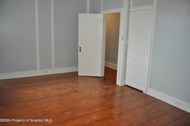 unfurnished bedroom with dark hardwood / wood-style flooring and a closet