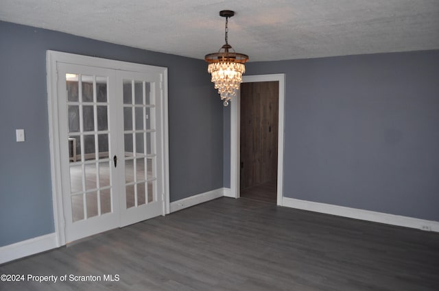 unfurnished dining area with french doors, dark wood-type flooring, a textured ceiling, and an inviting chandelier