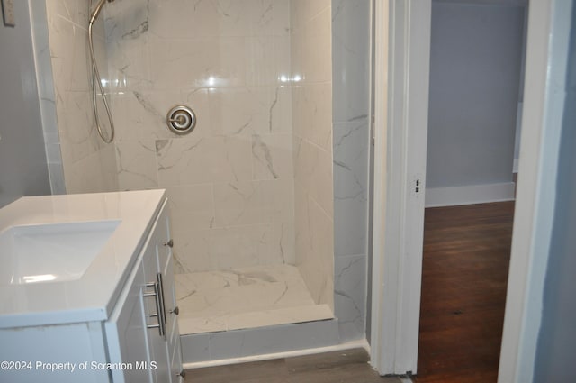 bathroom with a tile shower, vanity, and hardwood / wood-style flooring