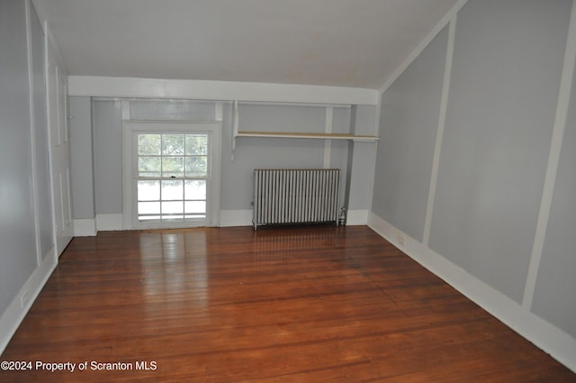 spare room featuring radiator heating unit and dark hardwood / wood-style floors