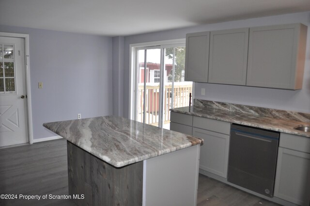 kitchen with gray cabinetry, a center island, dark wood-type flooring, black dishwasher, and light stone counters