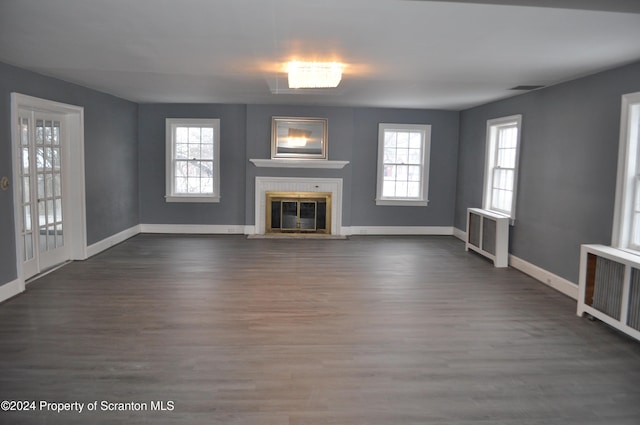 unfurnished living room featuring dark hardwood / wood-style flooring and radiator heating unit