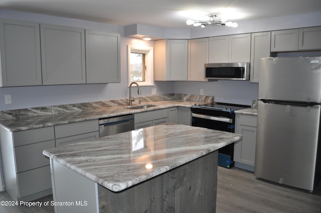 kitchen with gray cabinetry, light stone counters, sink, and stainless steel appliances