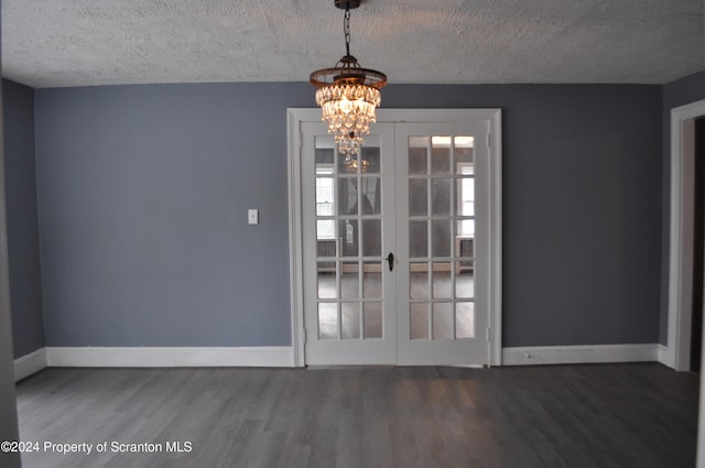 unfurnished dining area with a chandelier, wood-type flooring, a textured ceiling, and french doors