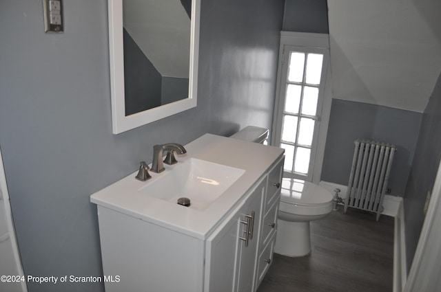 bathroom featuring radiator heating unit, vanity, hardwood / wood-style floors, and toilet