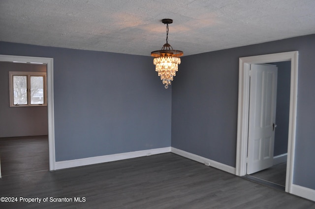 spare room with dark hardwood / wood-style flooring, a textured ceiling, and an inviting chandelier