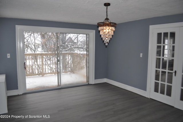 unfurnished dining area featuring french doors, dark wood-type flooring, a textured ceiling, and an inviting chandelier