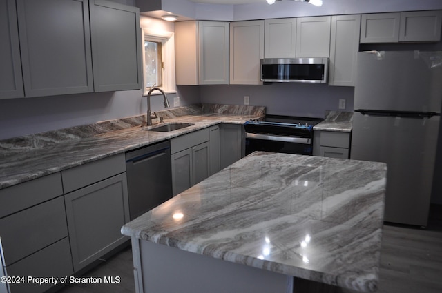 kitchen with gray cabinetry, light stone countertops, sink, and stainless steel appliances