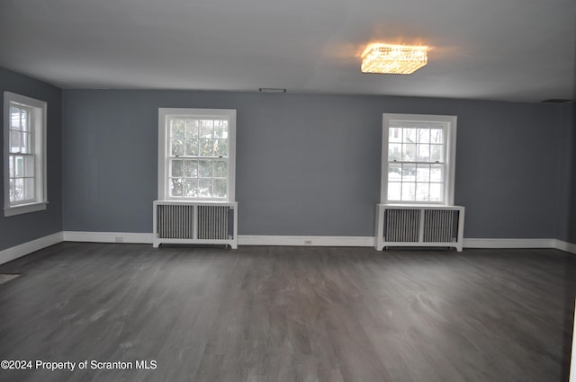 unfurnished room featuring radiator heating unit, dark hardwood / wood-style floors, and a healthy amount of sunlight