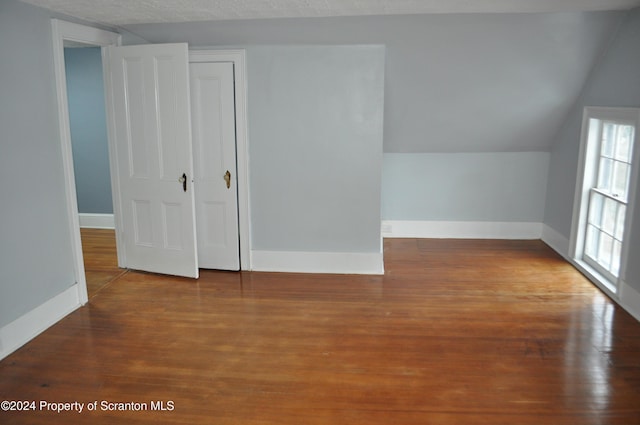 additional living space with wood-type flooring, a textured ceiling, and lofted ceiling