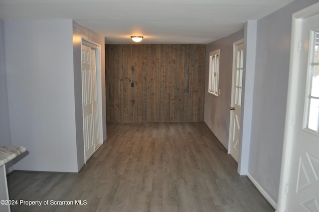 hallway with dark hardwood / wood-style floors and wood walls