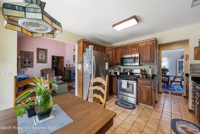 1200 Merion Cir, Clarks Summit, PA 18411 - kitchen featuring stainless steel appliances, light tile patterned floors, dark countertops, and brown cabinets