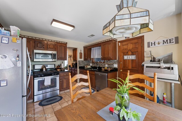 1200 Merion Cir, Clarks Summit, PA 18411 - kitchen with stainless steel appliances, light tile patterned flooring, dark countertops, and backsplash