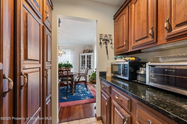 1200 Merion Cir, Clarks Summit, PA 18411 - kitchen with stainless steel microwave, brown cabinets, dark stone countertops, light wood-type flooring, and ornamental molding